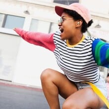 a person wearing the Samsung galaxy buds 2 earbuds rides a skateboard while bending down with arms out