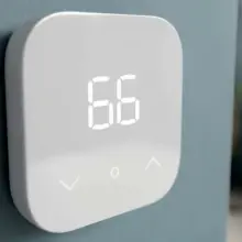 An Amazon Smart Thermostat hangs on a wall.