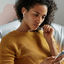 a person wearing second-generation apple airpods while looking at an iphone