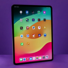 An iPad Pro standing against a purple background.