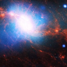 A space photo shows a spiral galaxy with a blue and white centre and orange spirals.