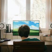 boy sitting in front of desktop computer with external speakers