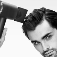 man drying his hair with dyson supersonic origin