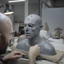 A man stands in front of a grey prosthetic head on a table.