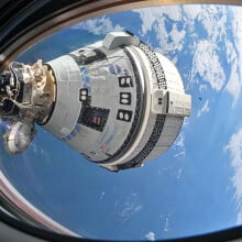 Starliner flying in space while docked at the International Space Station