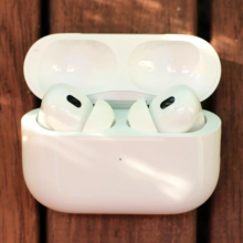 the second generation apple airpods pro in their charging case on a wooden surface