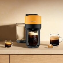 a mango-colored nespresso machine sits on a kitchen counter with several cups of coffee around it