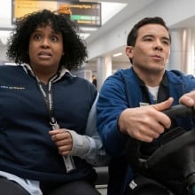 Mel and Rory race through JFK airport on a cart.