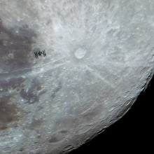 The International Space Station flies in front of the surface of the moon. 