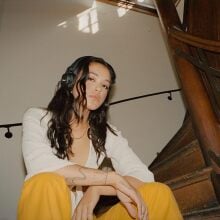 a person wearing the marshall major IV headphones sits on a set of dimly lit stairs