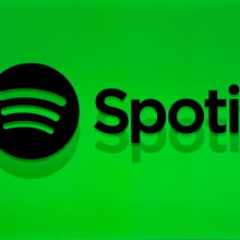 The silhouette of a man in front of a bright green backdrop that reads, "Spotify" with the Spotify logo next to it. 