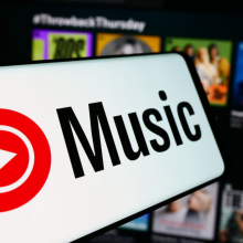 In this photo illustration, a mobile phone with the logo of American music streaming service YouTube Music is seen in front of business website. 