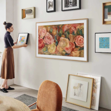 woman hanging art on wall