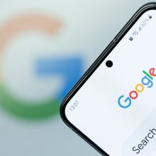 Google search app on smartphone screen close up with blurred logo background.