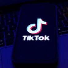 TikTok logo displayed on a phone screen and a laptop keyboard 