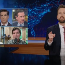 A man in a suit sits behind a talk show desk. In the top-left are six images of other men and women on TV.