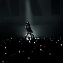 Charli XCX illuminated on stage. 