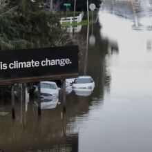 A billboard rises above a flooded street. It reads, "This is climate change."