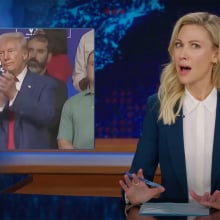 A woman sits behind a talk show desk. In the top-left is an image of a man in a suit at a town hall.