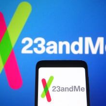 23andme logo on a phone in front of a blue background with the same logo