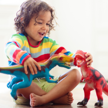 small child laughing and playing with dinosaur toys 