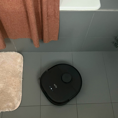 Eufy X10 Pro Omni robot vacuum mopping tile floor in bathroom near shower and bath mats