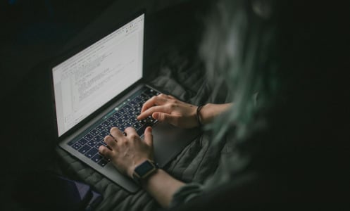 man working on laptop screen in dark room