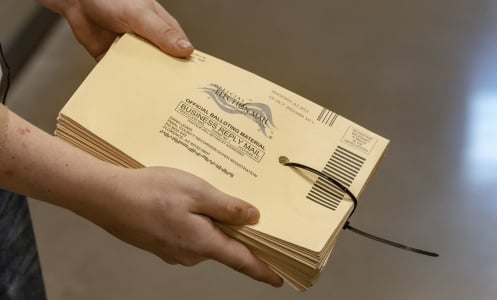 A poll worker holds a stack of ballot envelopes. 