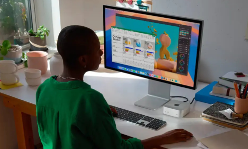 A person sitting at a desk using a Mac Mini.