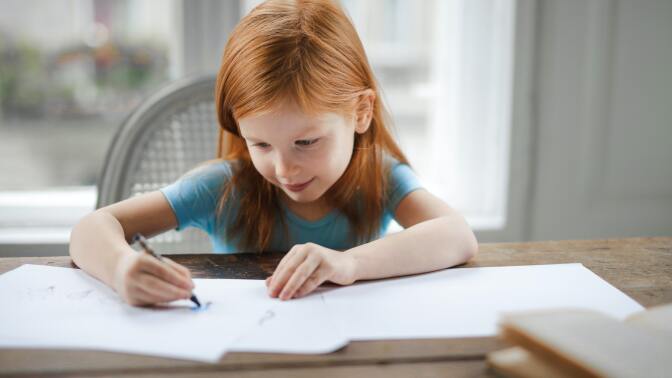 girl sitting at table in front of open notebooks