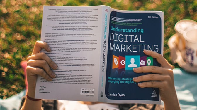 Hands holding a book titled "understanding digital marketing"