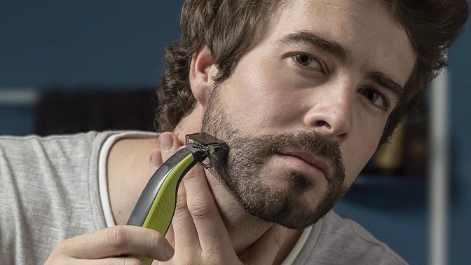 Person using a Philips Norelco OneBlade electric razor to shave.