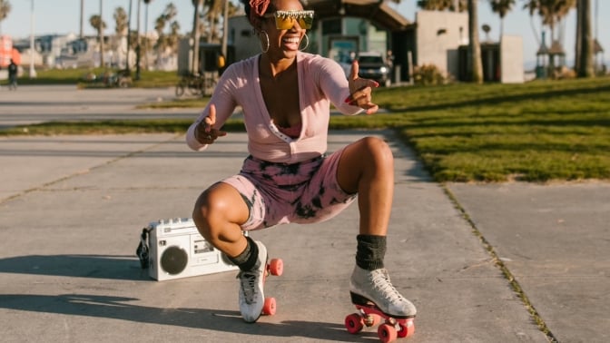 Black woman posing on roller skates with boombox behind them.