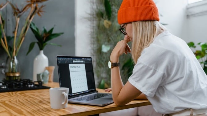 Person in orange hat using laptop