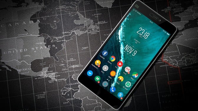 cell phone with teal background against a grey map