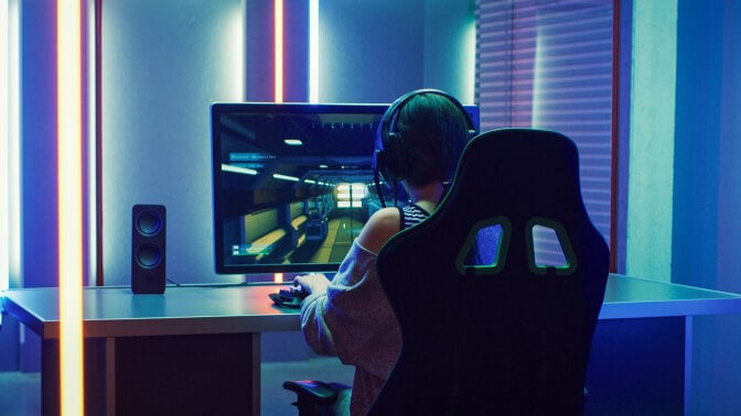 woman on computer playing video games with colorful LED lighting