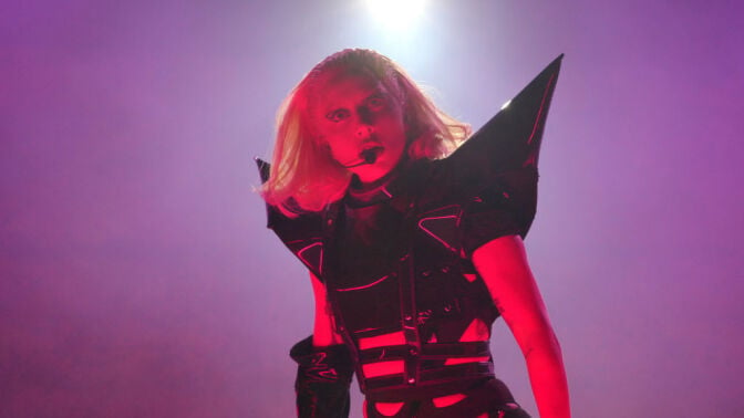 Lady Gaga performing in a black bodysuit with pointy shoulder pieces.