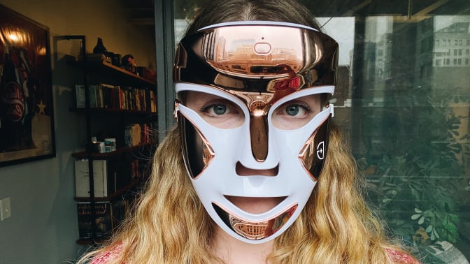 woman wearing gold and white LED face mask