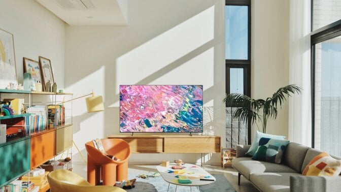 Samsung TV with colorful water screensaver on TV stand in sunlit room