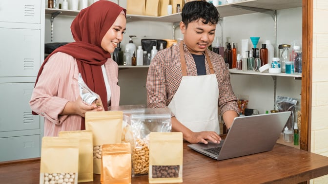 Two coworkers using a laptop in a food store