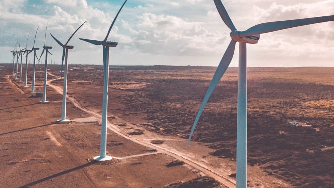 Wind turbines lined up on a vast field. 