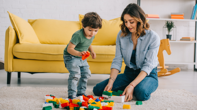 Mother and son playing with lego on carpet in living room