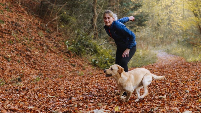 woman playing with dog in the woods