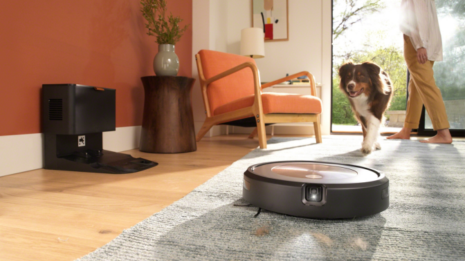 Roomba with headlight cleaning carpet with dog and person's feet in background