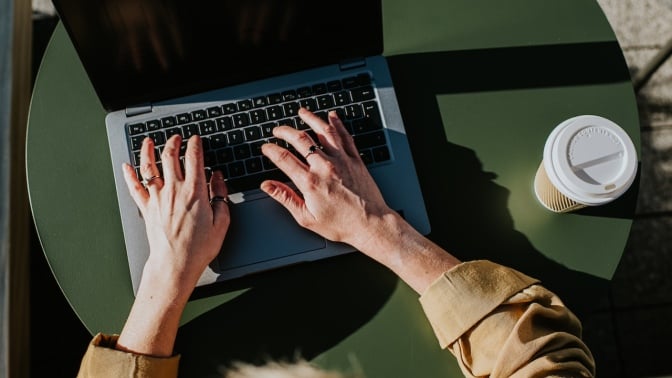 Person typing on laptop while sitting at a table