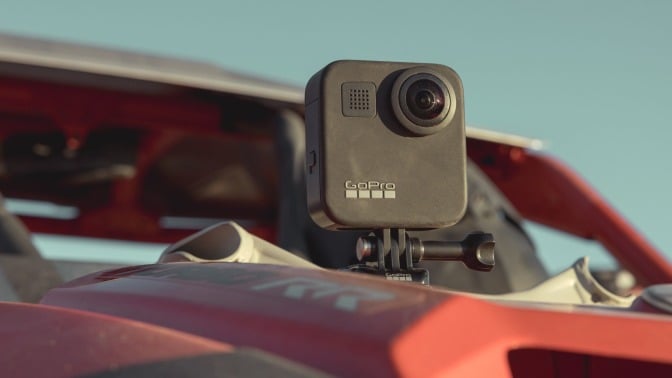 a GoPro Max camera sits mounted on the hood of a dusty car in the sun