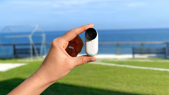 The Insta360 GO 3S being held between two fingers.