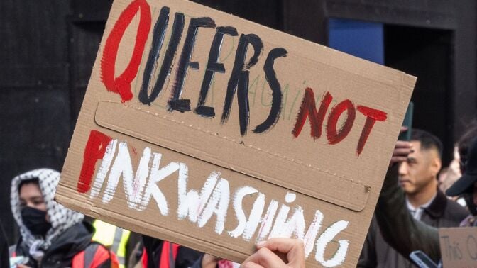 A pro-Palestinian protester from the Free Palestine Coalition holds up a sign criticizing Israeli 'pinkwashing' during a march through central London.