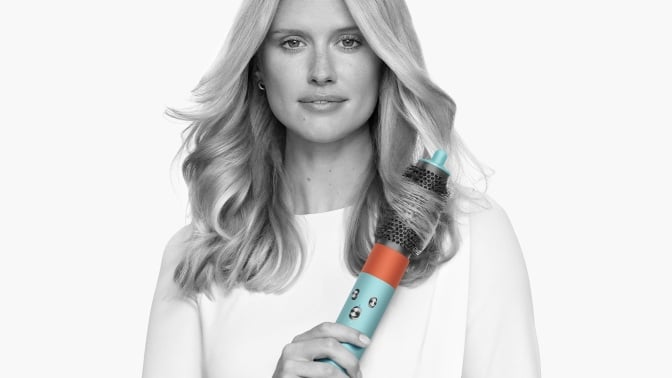 person styling hair with volumizing round brush attachment of dyson airwrap