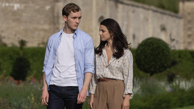 Robert and Yasmin walk through a garden.